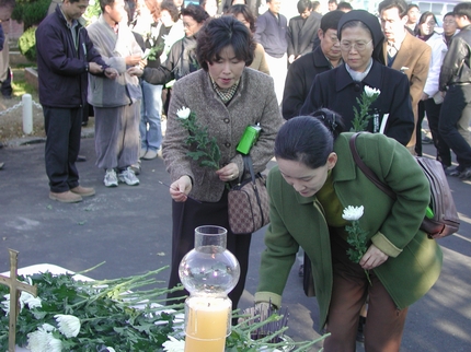 수녀를 비롯한 기도회에 참석참석자들이 두 영정 앞에 꽃을 바치며 헌화하고 있다. 